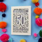 50th Anniversary Card with '50 amazing years' design on a blue background with colourful pom-poms.