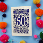 50th Anniversary Card with '50 amazing years' design on a blue background with colourful pom-poms.