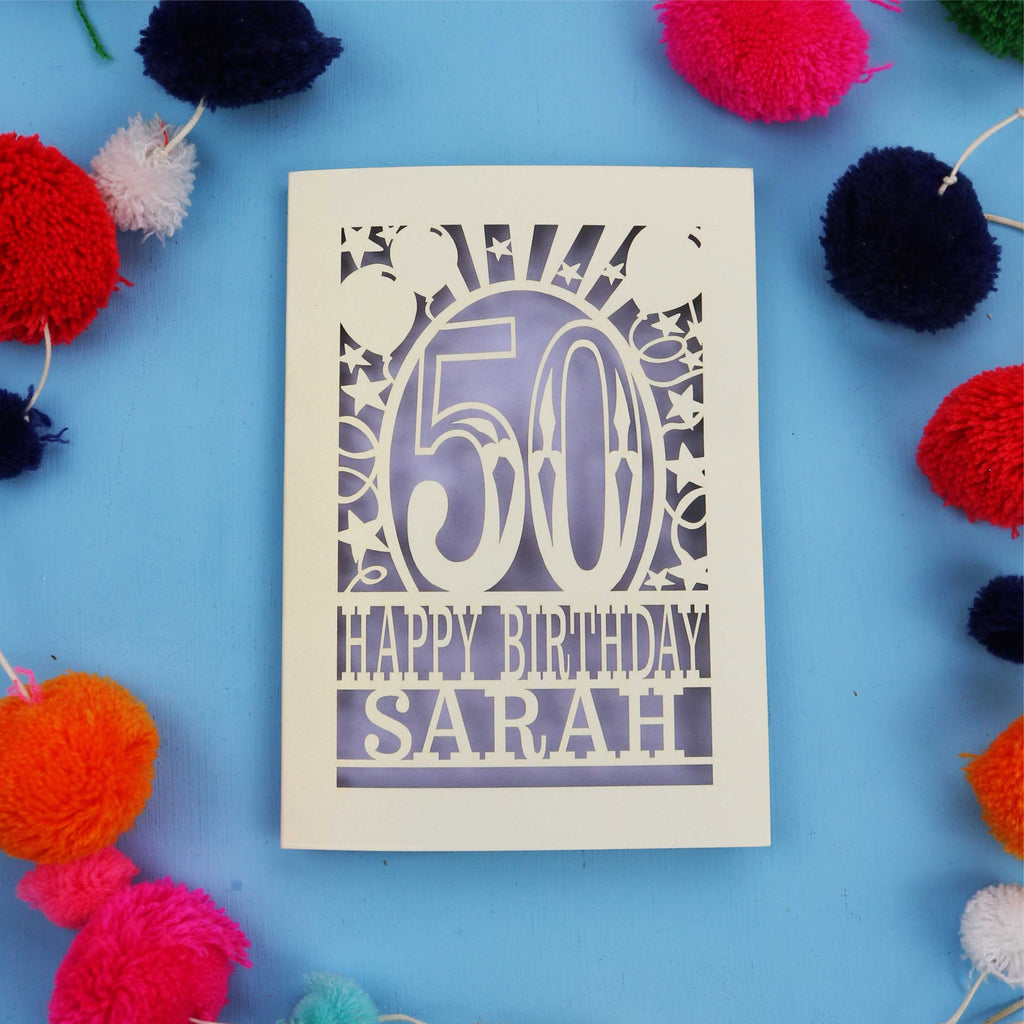 Laser cut Happy 50th birthday card with colourful pom-poms on a blue background