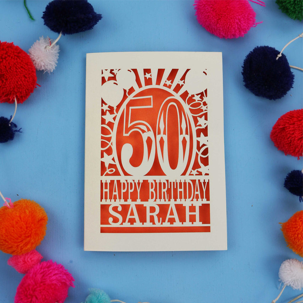Laser cut Happy 50th birthday card with colourful pom-poms on a blue background