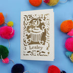 A 50th birthday Card with '50' and 'Lesley' on a blue background with colourful pom-poms