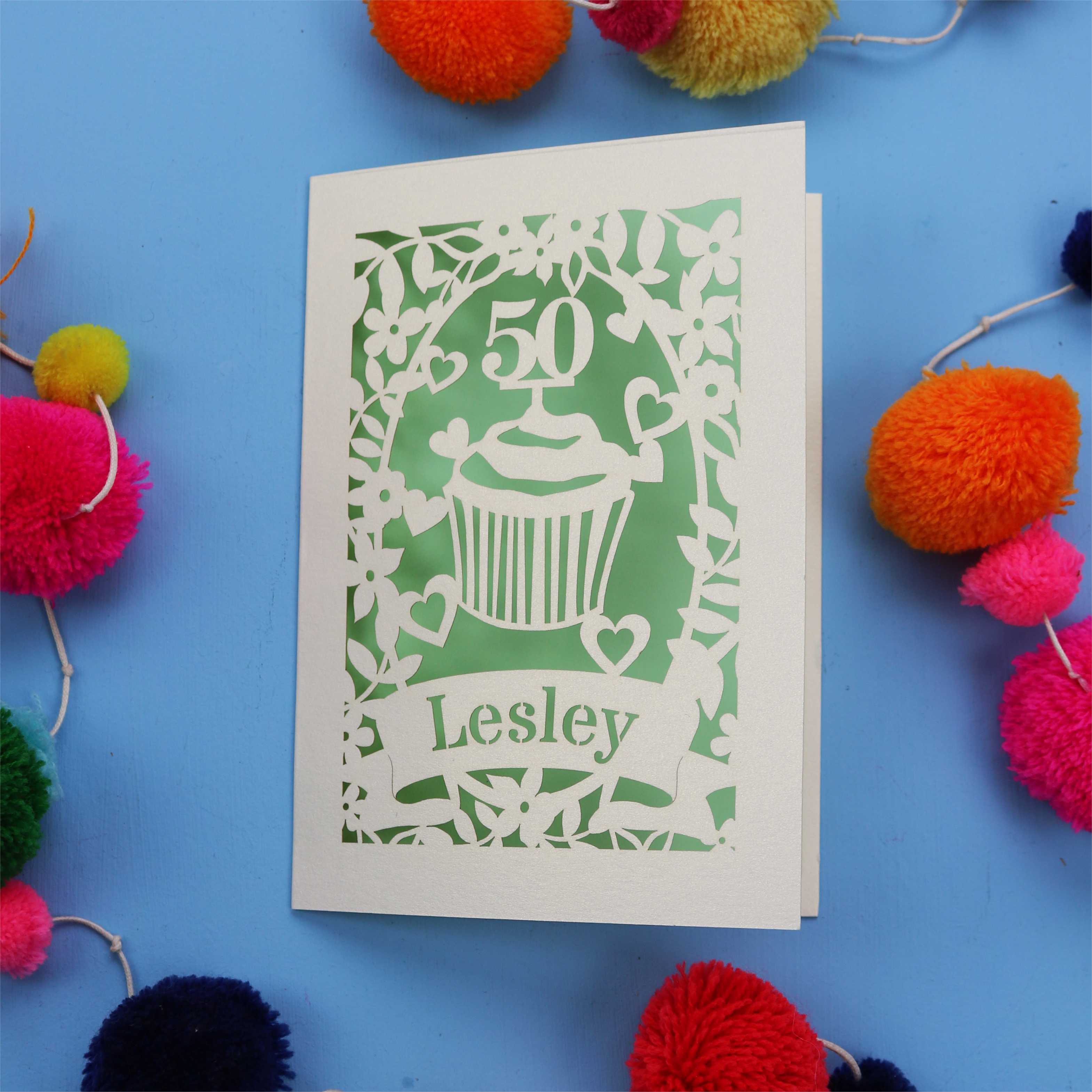 A 50th birthday Card with '50' and 'Lesley' on a blue background with colourful pom-poms