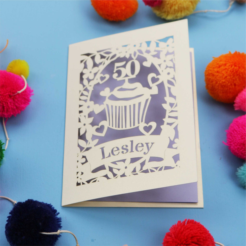 A 50th birthday Card with '50' and 'Lesley' on a blue background with colourful pom-poms