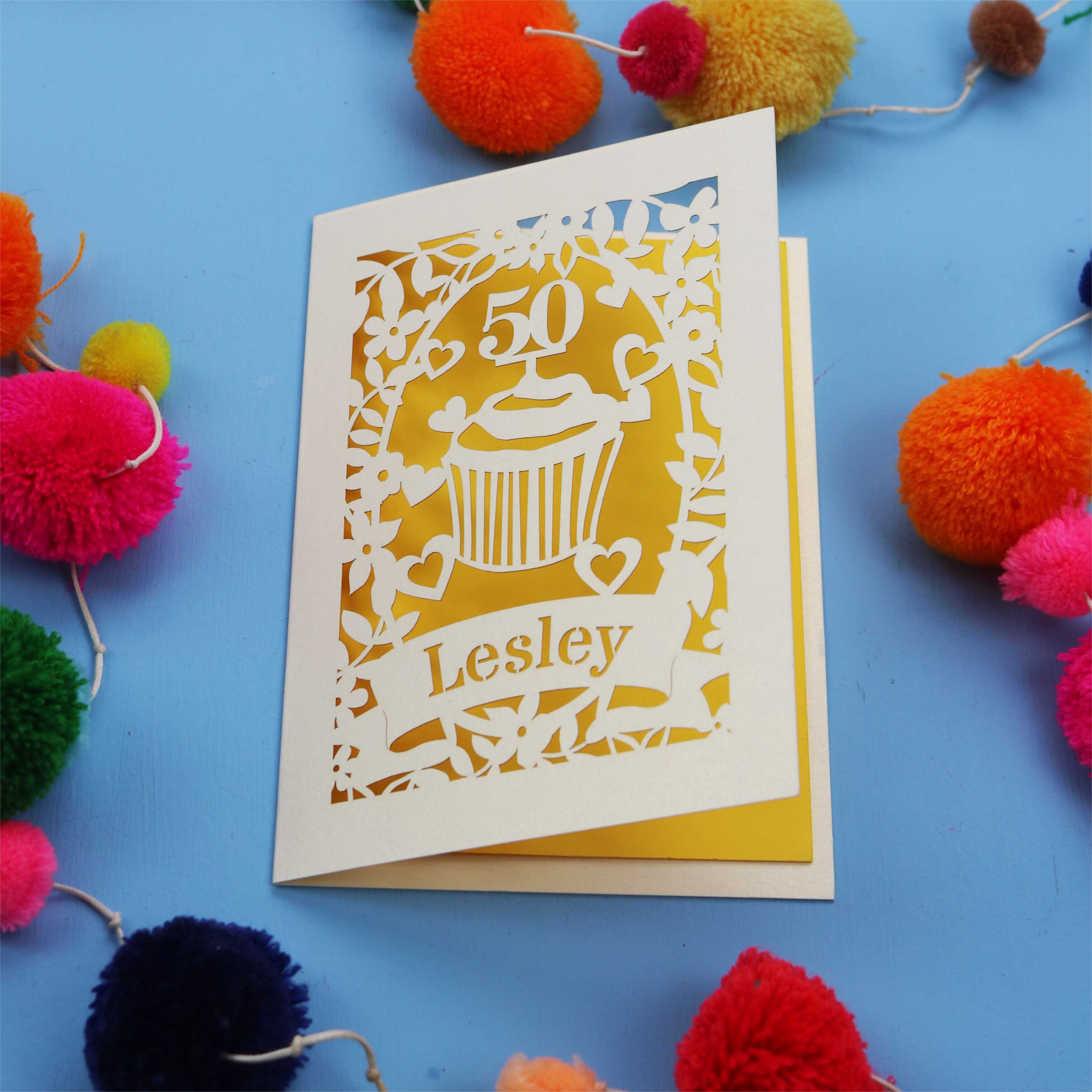 A 50th birthday Card with '50' and 'Lesley' on a blue background with colourful pom-poms