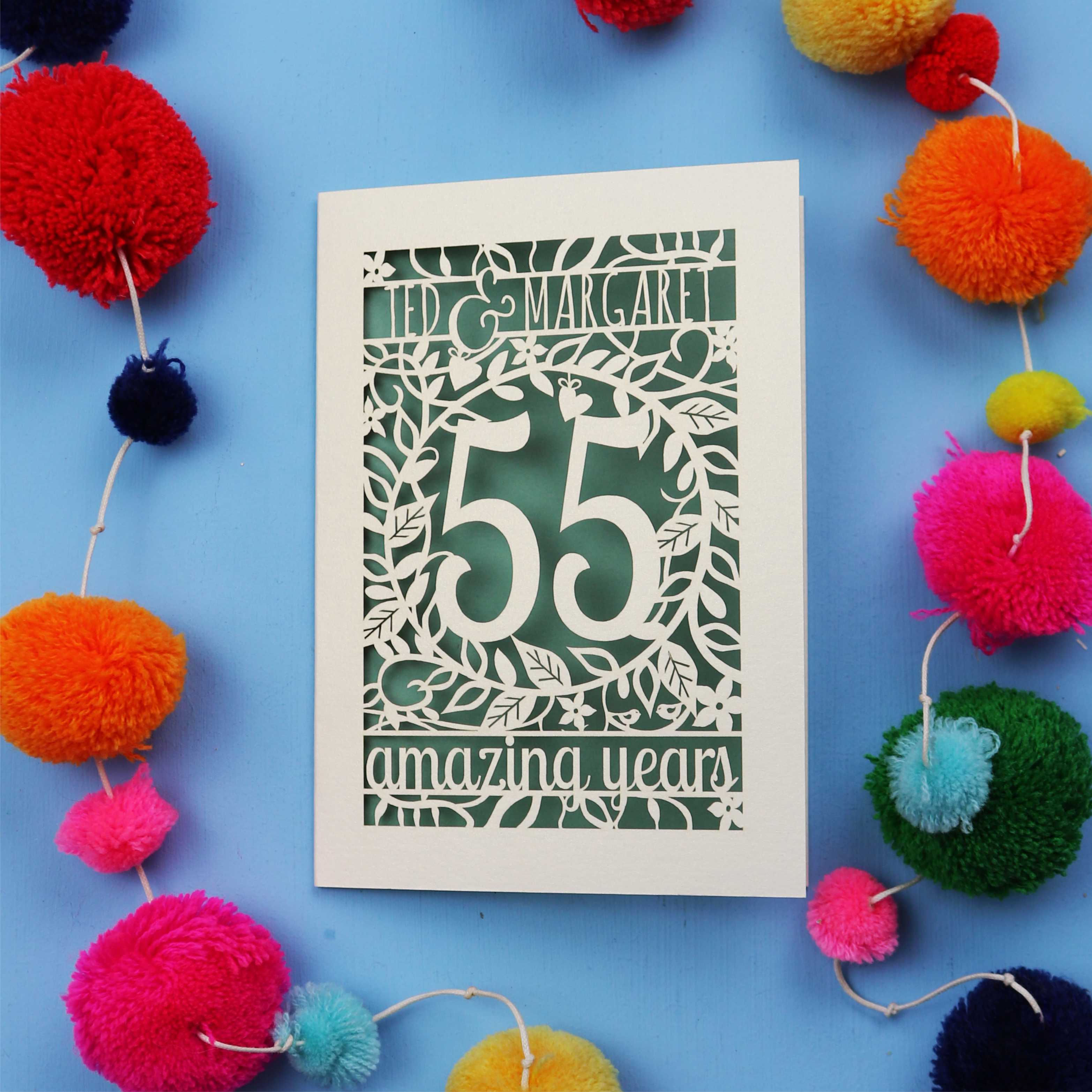 Emerald anniversary Card with '55 amazing years' design on a blue background with colourful pom-poms.