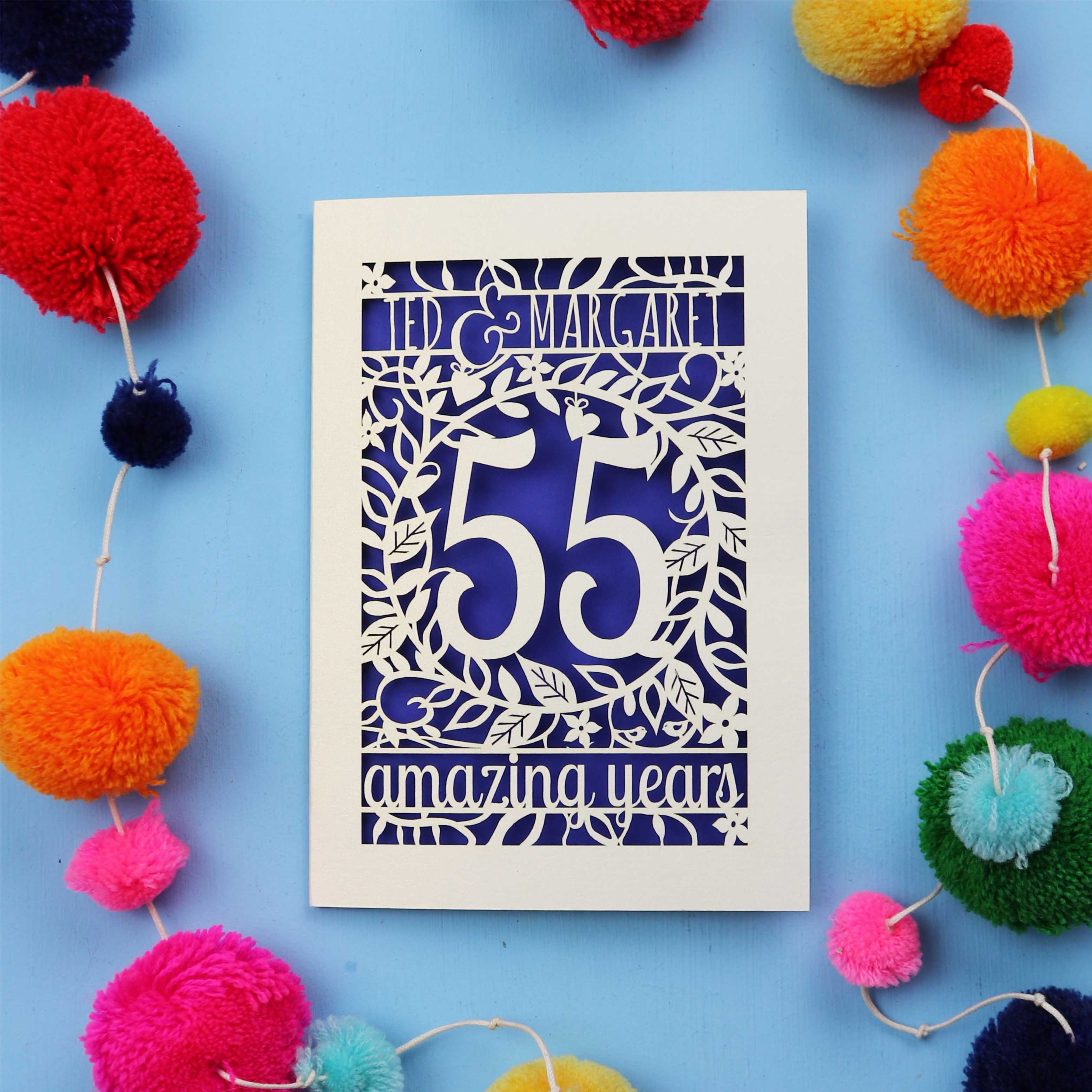 Emerald anniversary Card with '55 amazing years' design on a blue background with colourful pom-poms.