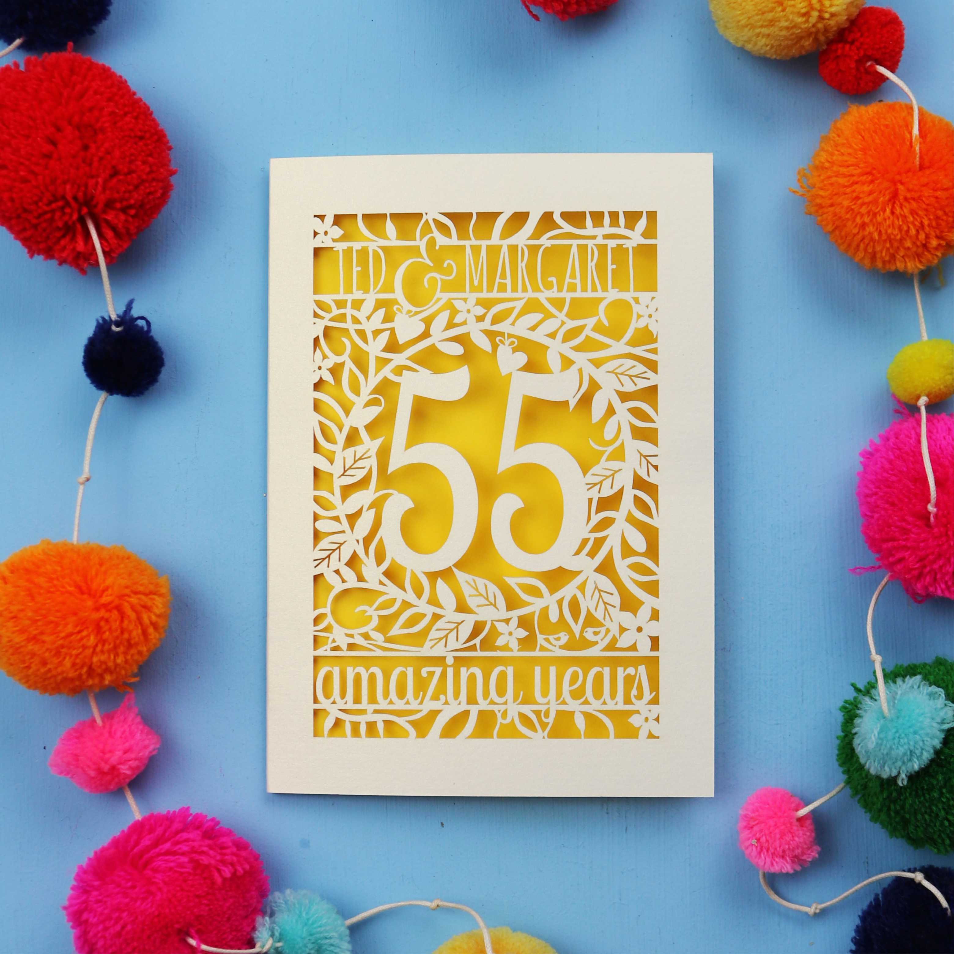 Personalised Emerald wedding anniversary Card with '55 amazing years' design on a blue background with colourful pom-poms.