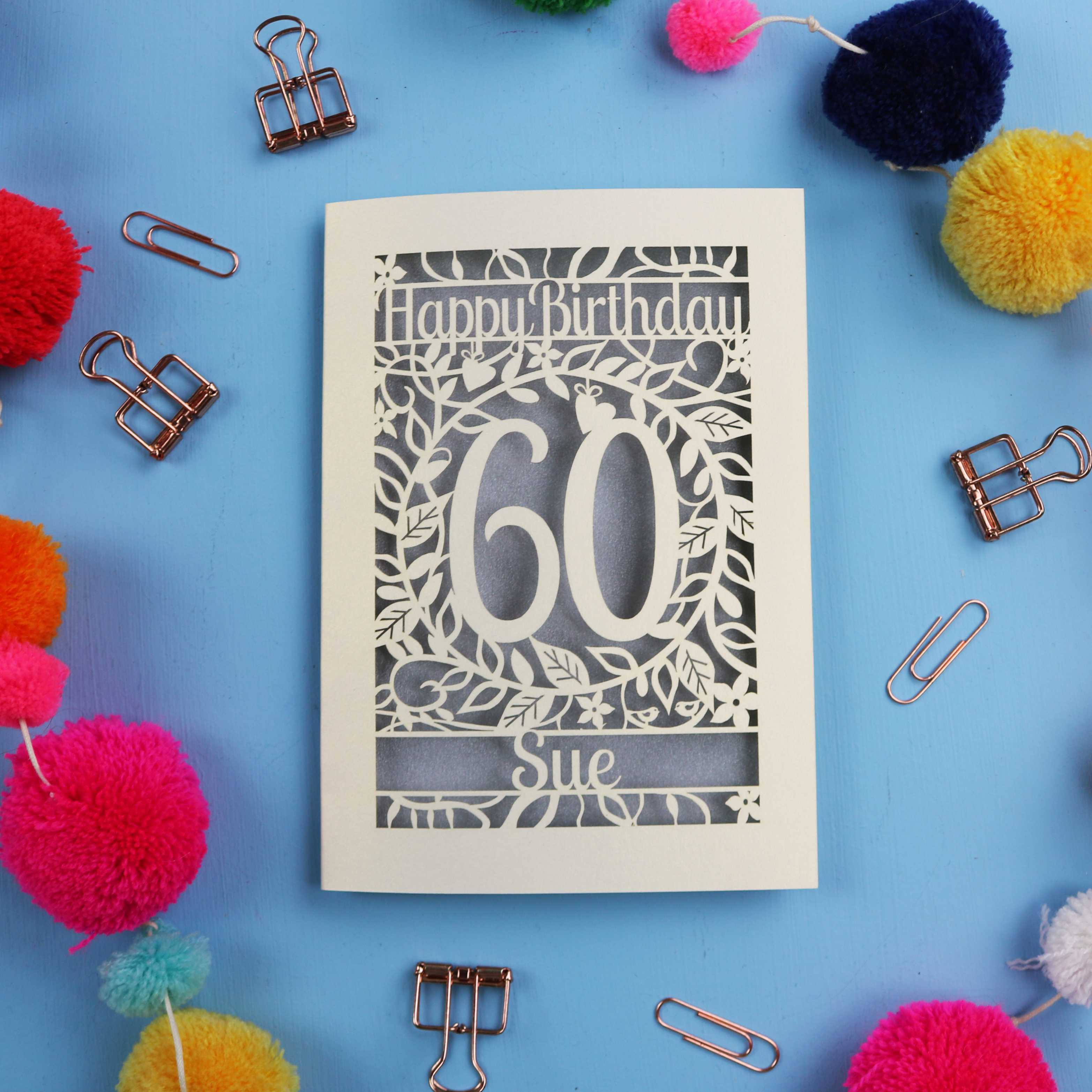 60th Birthday card with 'Happy Birthday 60 Sue' on a blue background with colourful pom-poms and paper clips.
