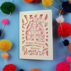 Laser Cut 60th Birthday card with personalized name surrounded by colourful pom-poms on a blue background