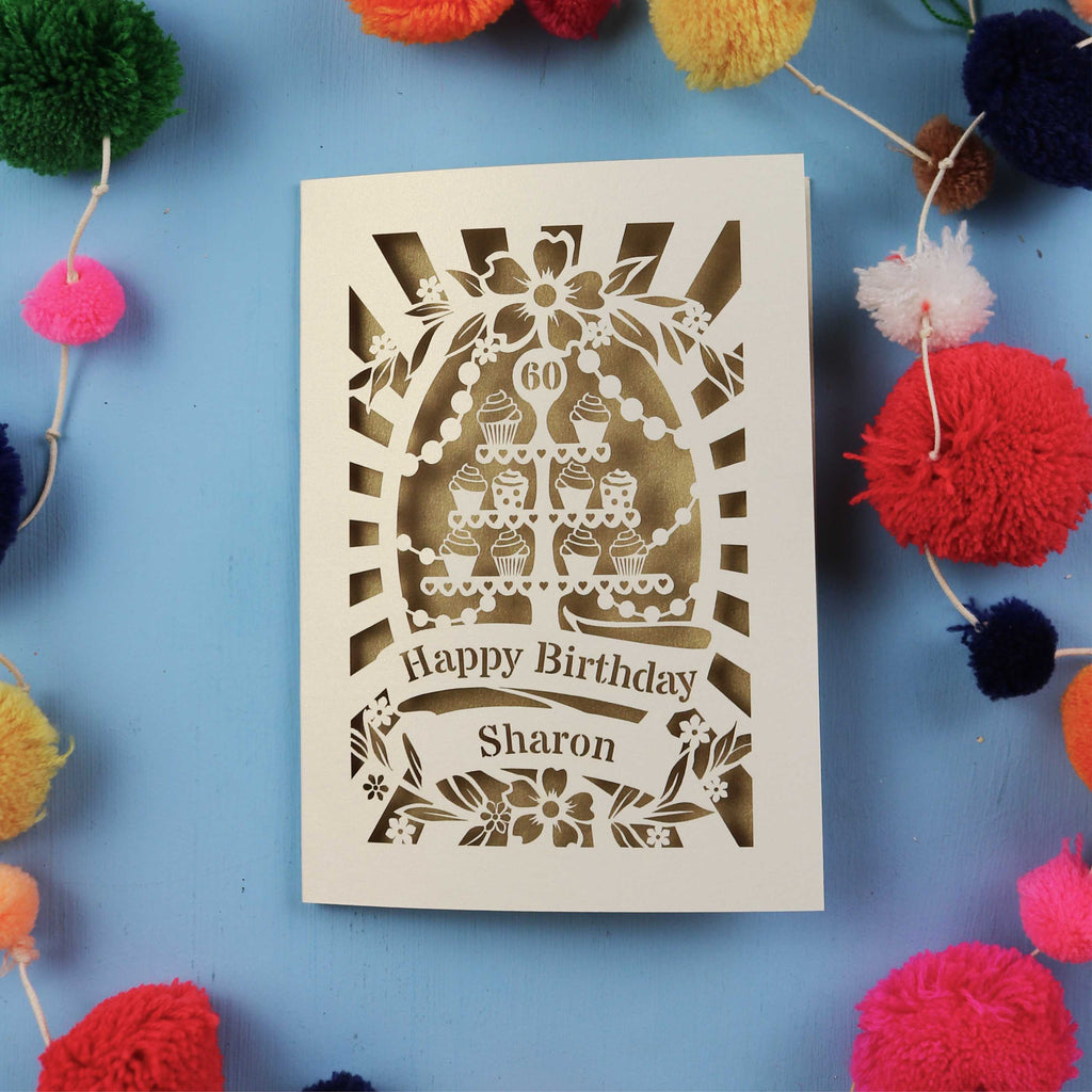 Laser Cut 60th Birthday card with personalized name surrounded by colourful pom-poms on a blue background