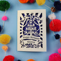 Laser Cut 60th Birthday card with personalized name surrounded by colourful pom-poms on a blue background
