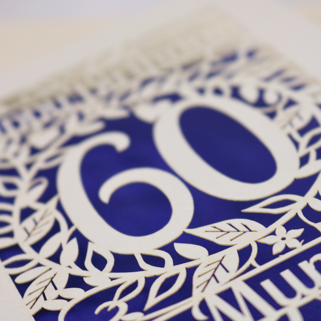 A laser cut 60th birthday card with cut out floral border and "Happy Birthday" with a number 60 in the centre 