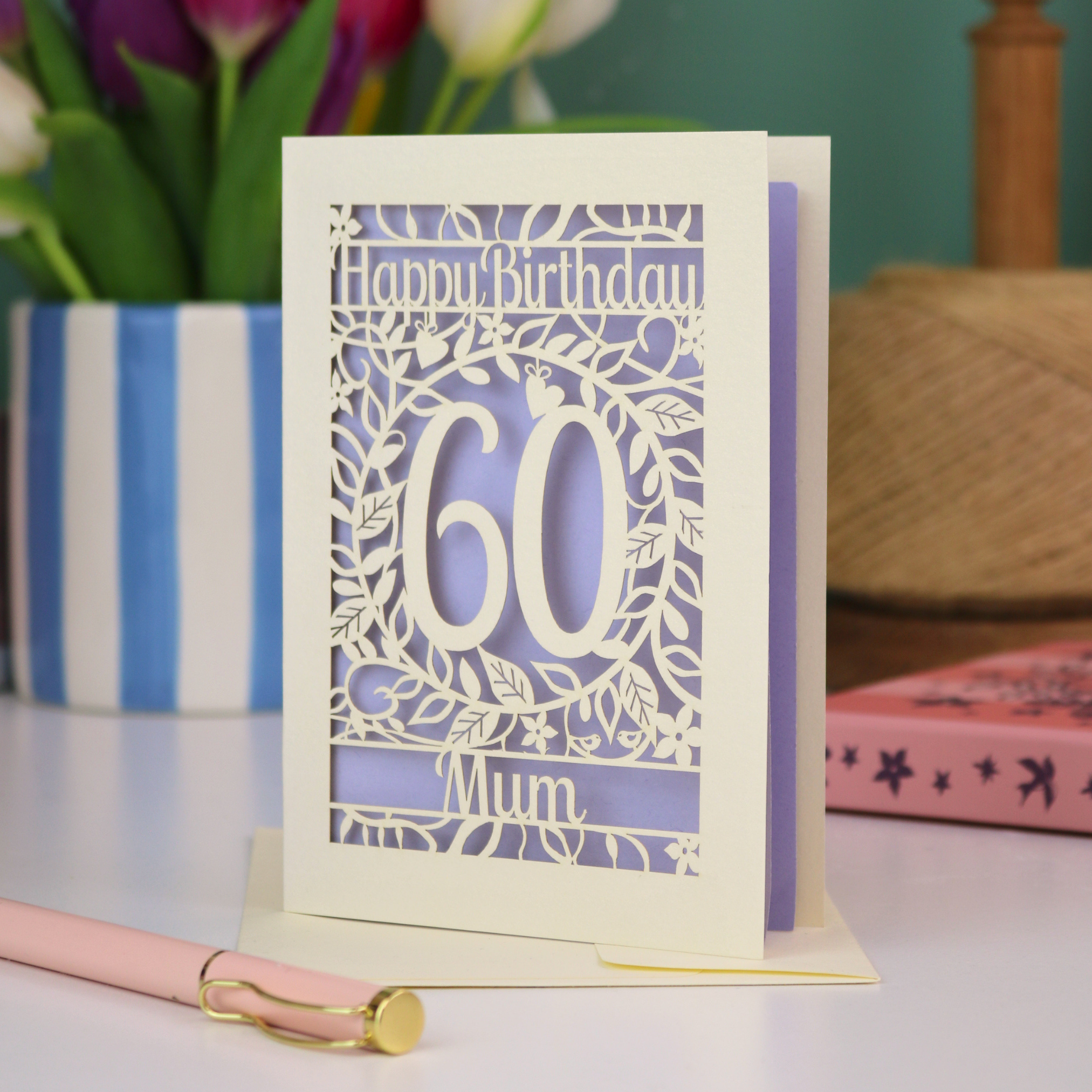 A personalised 60th birthday card with cut out floral border and "Happy Birthday" with a number 60 in the centre and personalised at the bottom with a name. 