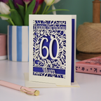 A laser cut 60th birthday card with cut out floral border and "Happy Birthday" with a number 60 in the centre and personalised at the bottom with a name. 