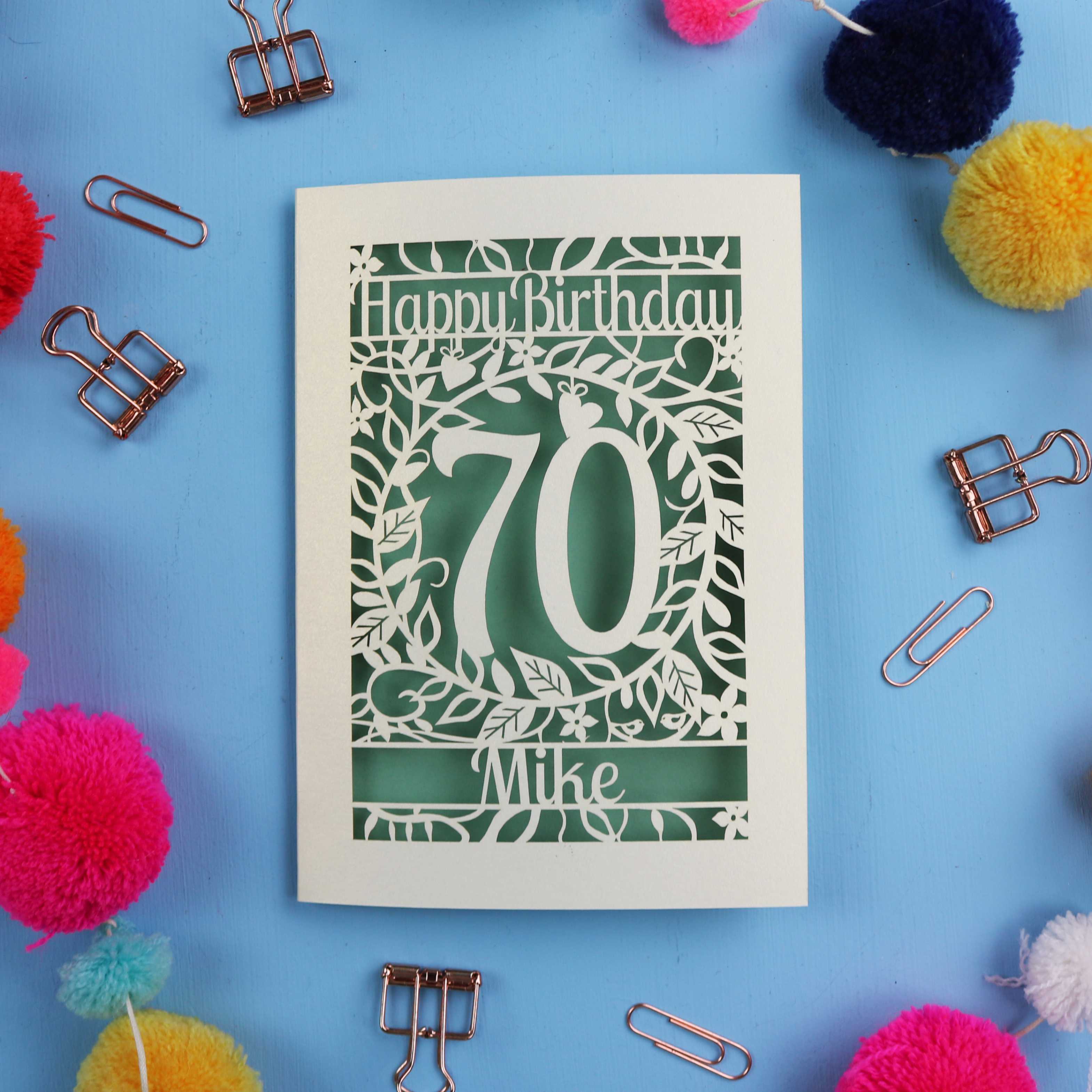 A laser cut 70th birthday card with 'Happy Birthday' and personalised with the recipient's name. The number 70 is in the centre, surrounded by leaf and floral cut out designs. 