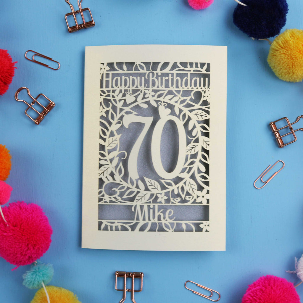 A laser cut 70th birthday card with 'Happy Birthday' and personalised with the recipient's name. The number 70 is in the centre, surrounded by leaf and floral cut out designs. 