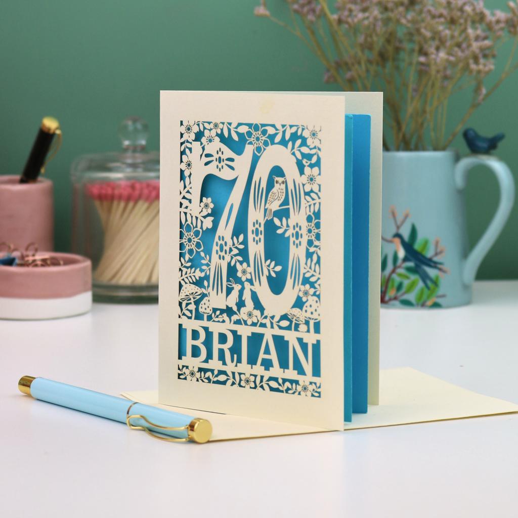 Luxury 70th birthday card with floral  woodland design and '70' 'Brian' text on a table.