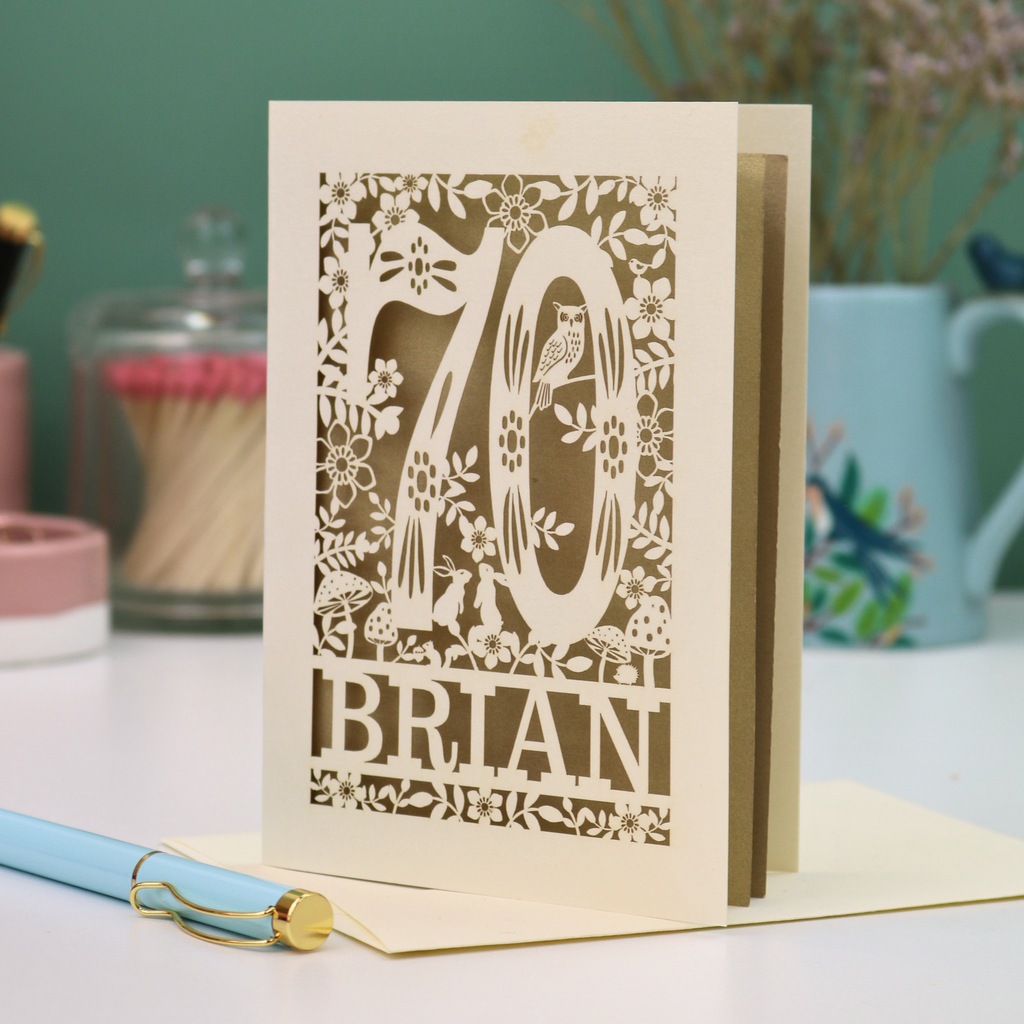 Decorative keepsake 70th birthday card with floral  woodland design and '70' 'Brian' text on a table.