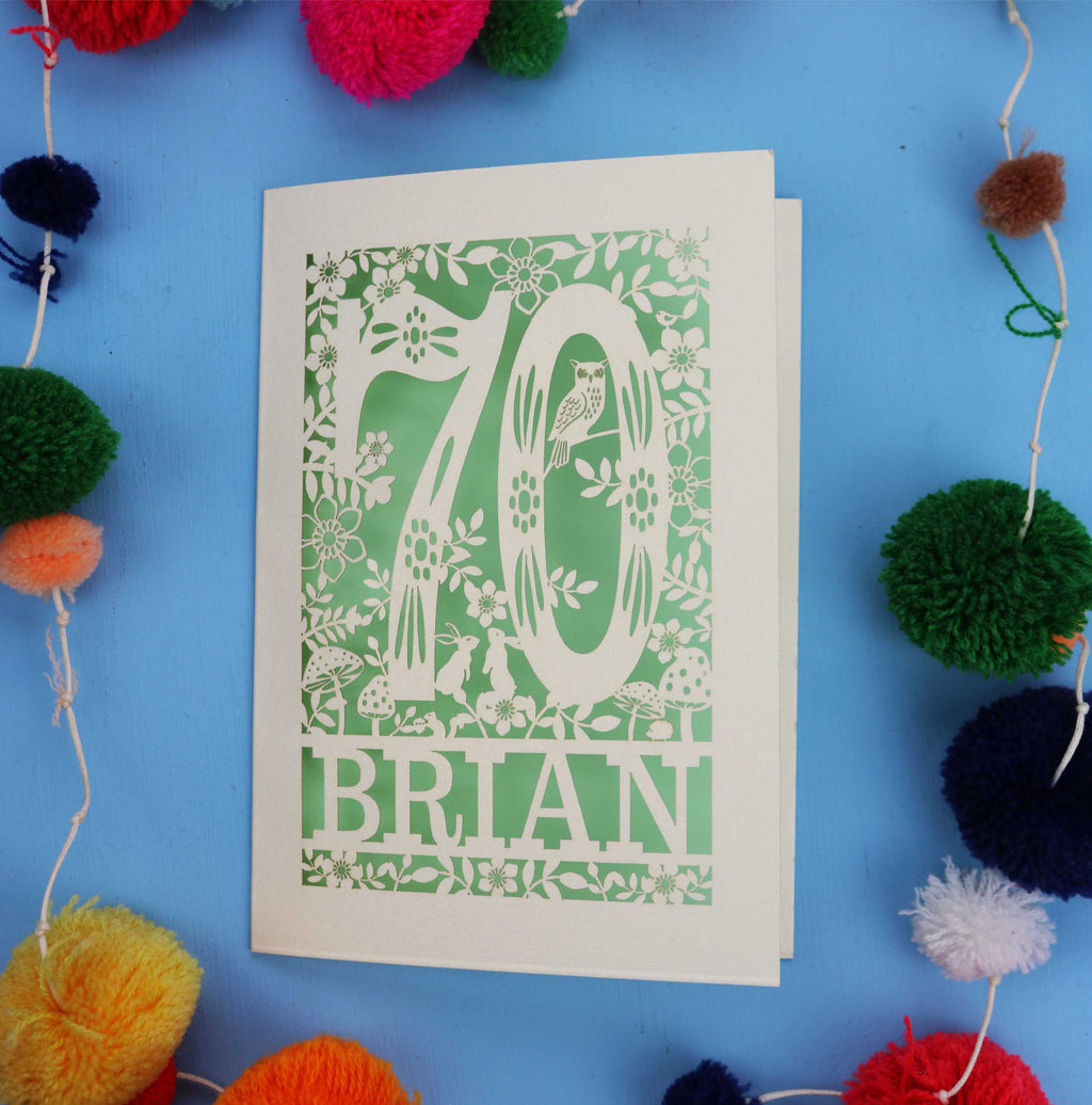 A personalised 70th birthday card featuring the number 70 and woodland cut out details. 