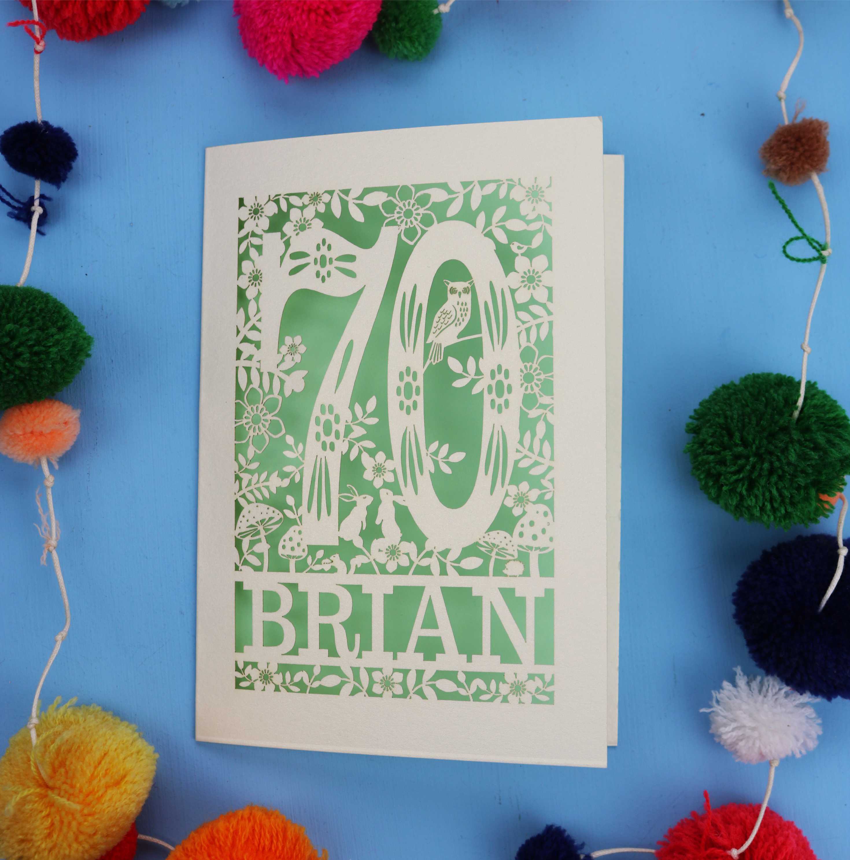 A personalised 70th birthday card featuring the number 70 and woodland cut out details. 