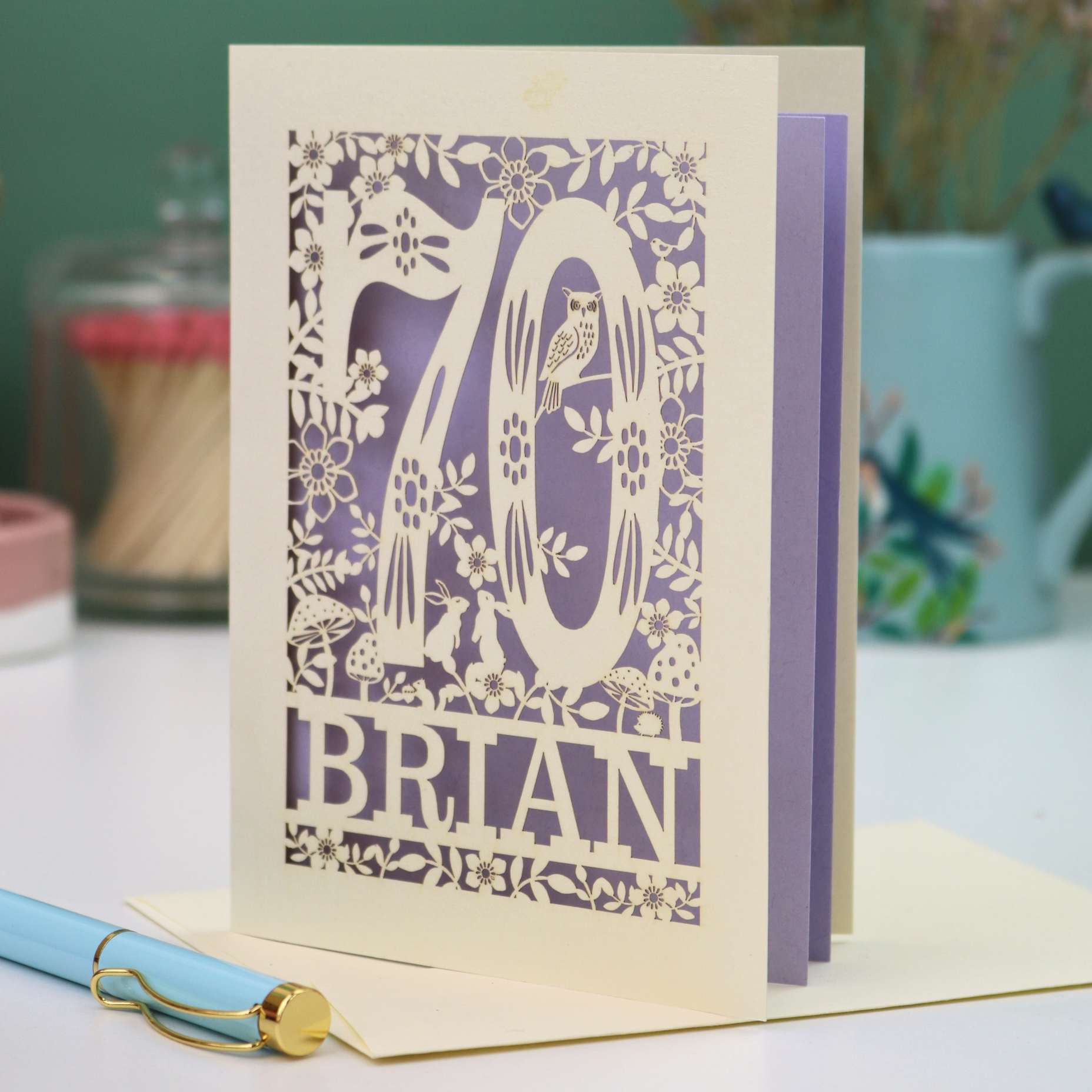 Personalised 70th birthday card with floral  woodland design and '70' 'Brian' text on a table.