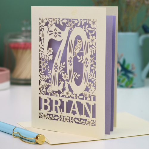 Personalised 70th birthday card with floral  woodland design and '70' 'Brian' text on a table.