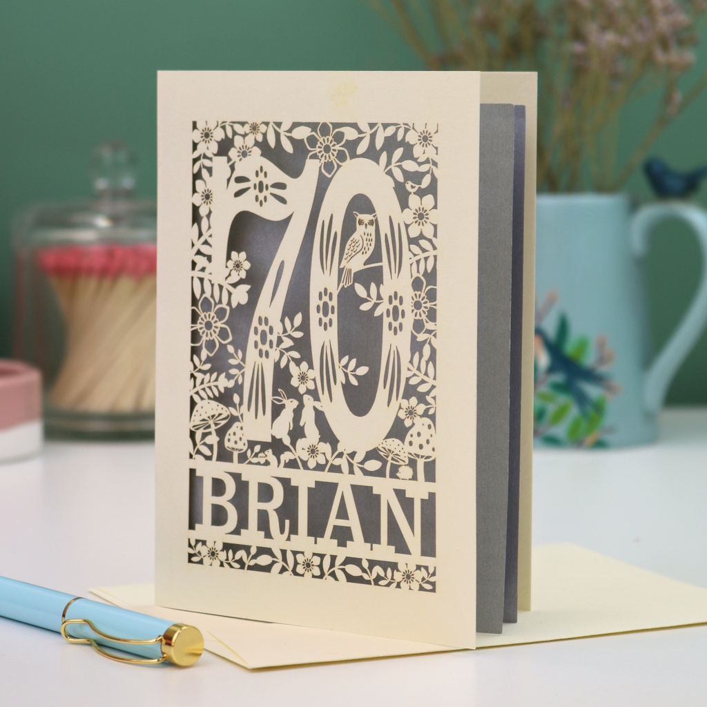 Luxury 70th birthday card with floral  woodland design and '70' 'Brian' text on a table.