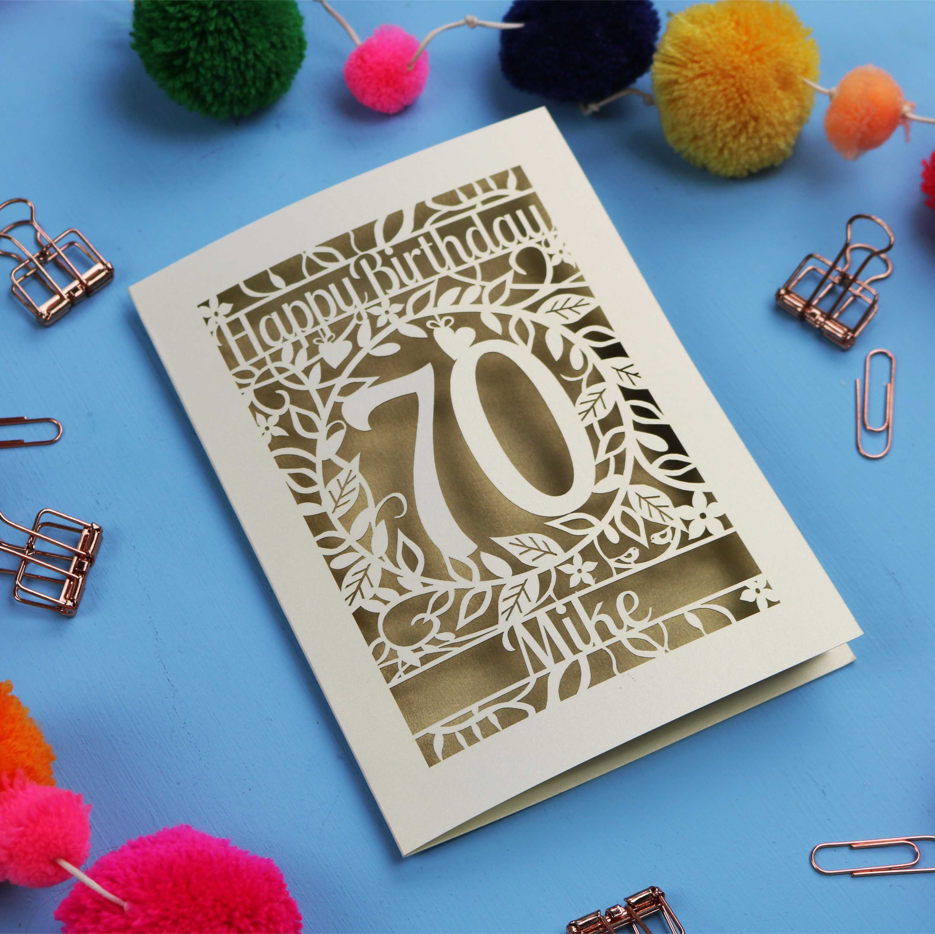 A laser cut 70th birthday card with 'Happy Birthday' and personalised with the recipient's name. The number 70 is in the centre, surrounded by leaf and floral cut out designs. 