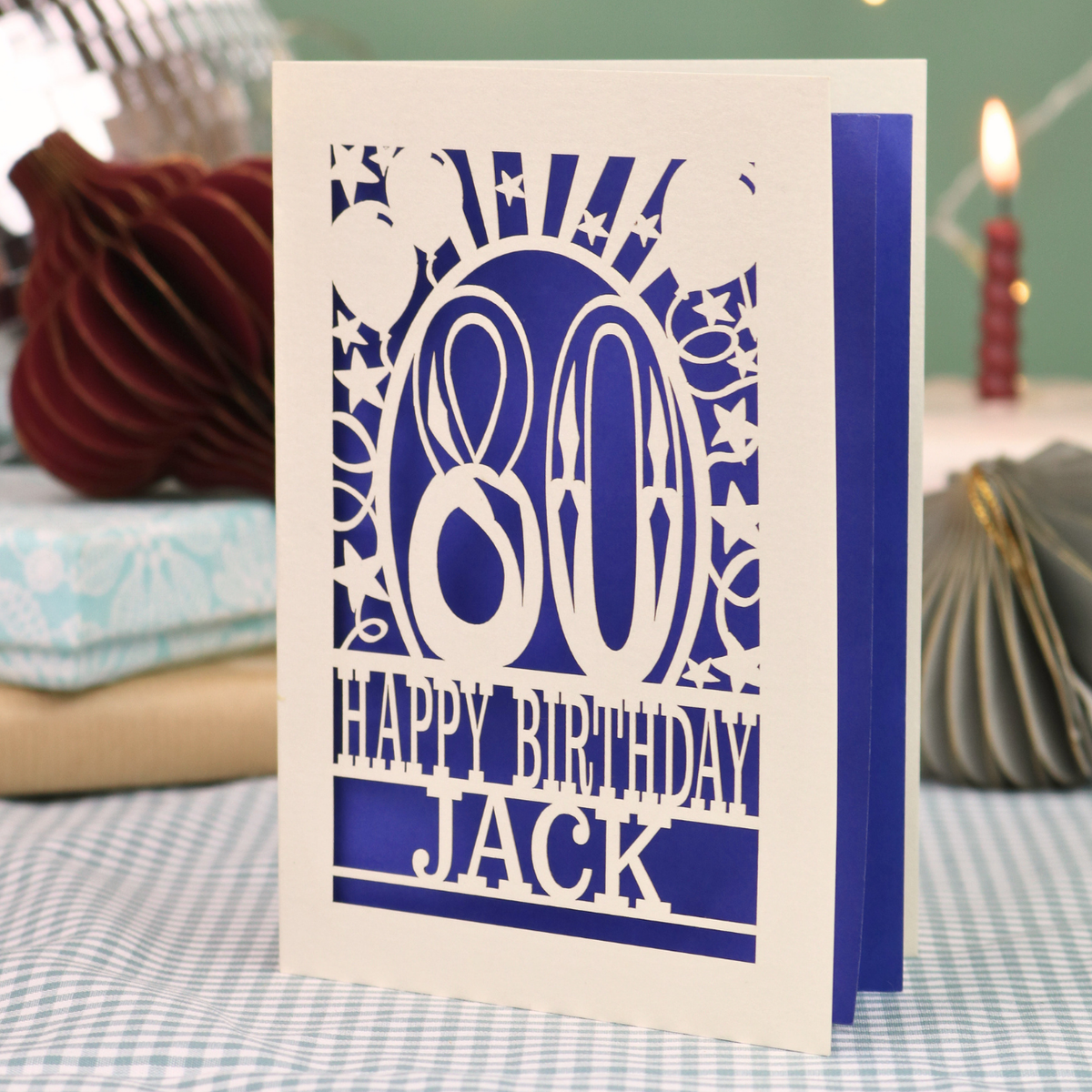 A personalised birthday card for 80th birthday, with decorative number '80' and text, 'Happy Birthday Jack', and a cut out border with stars and balloons. 