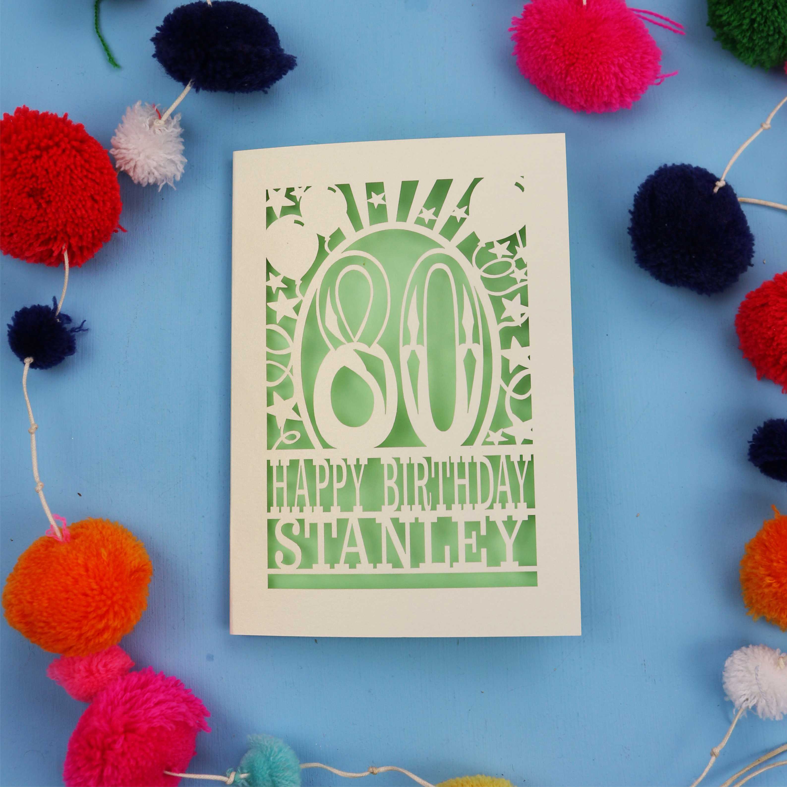 80th Birthday card with 'Happy Birthday Stanley' on a blue background with colourful pom-poms.