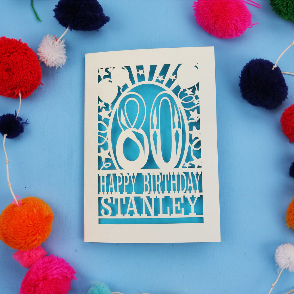 80th Birthday card with 'Happy Birthday Stanley' on a blue background with colourful pom-poms.