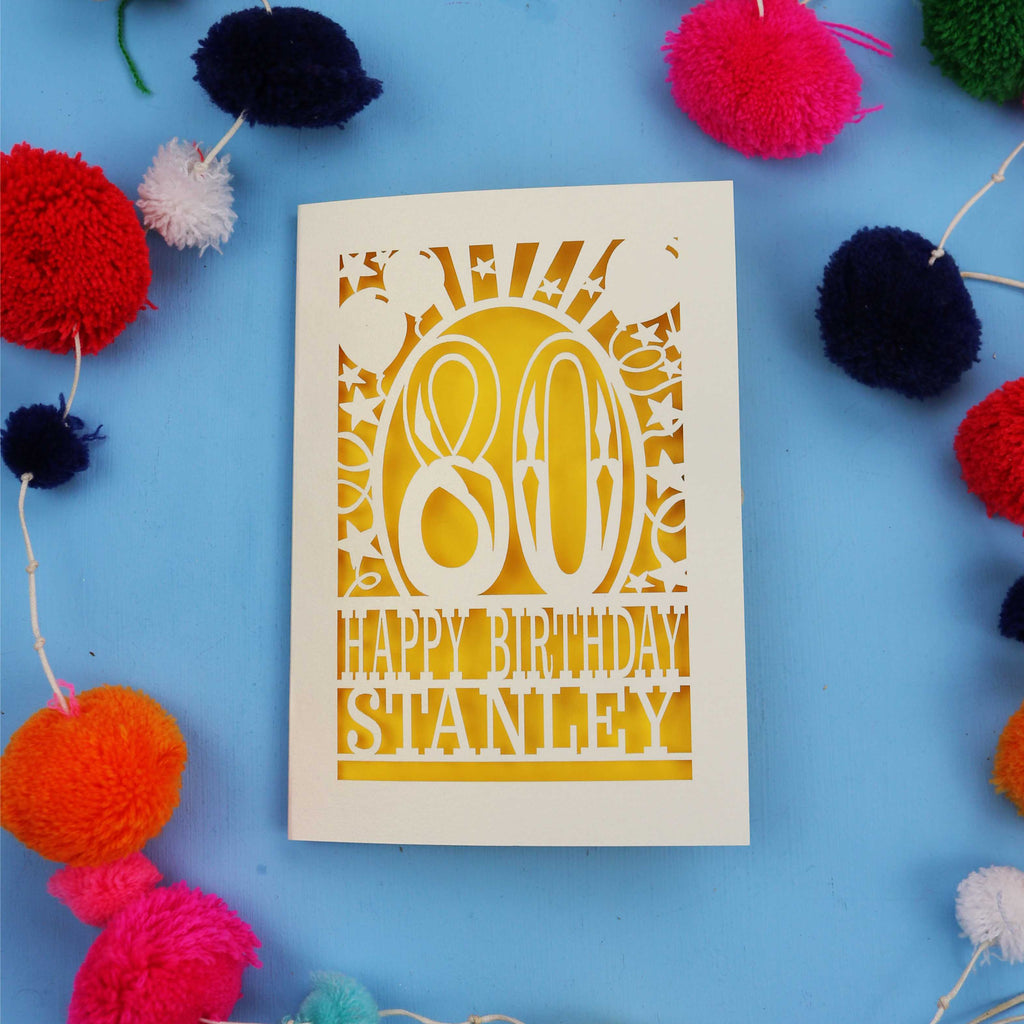 80th Birthday card with 'Happy Birthday Stanley' on a blue background with colourful pom-poms.