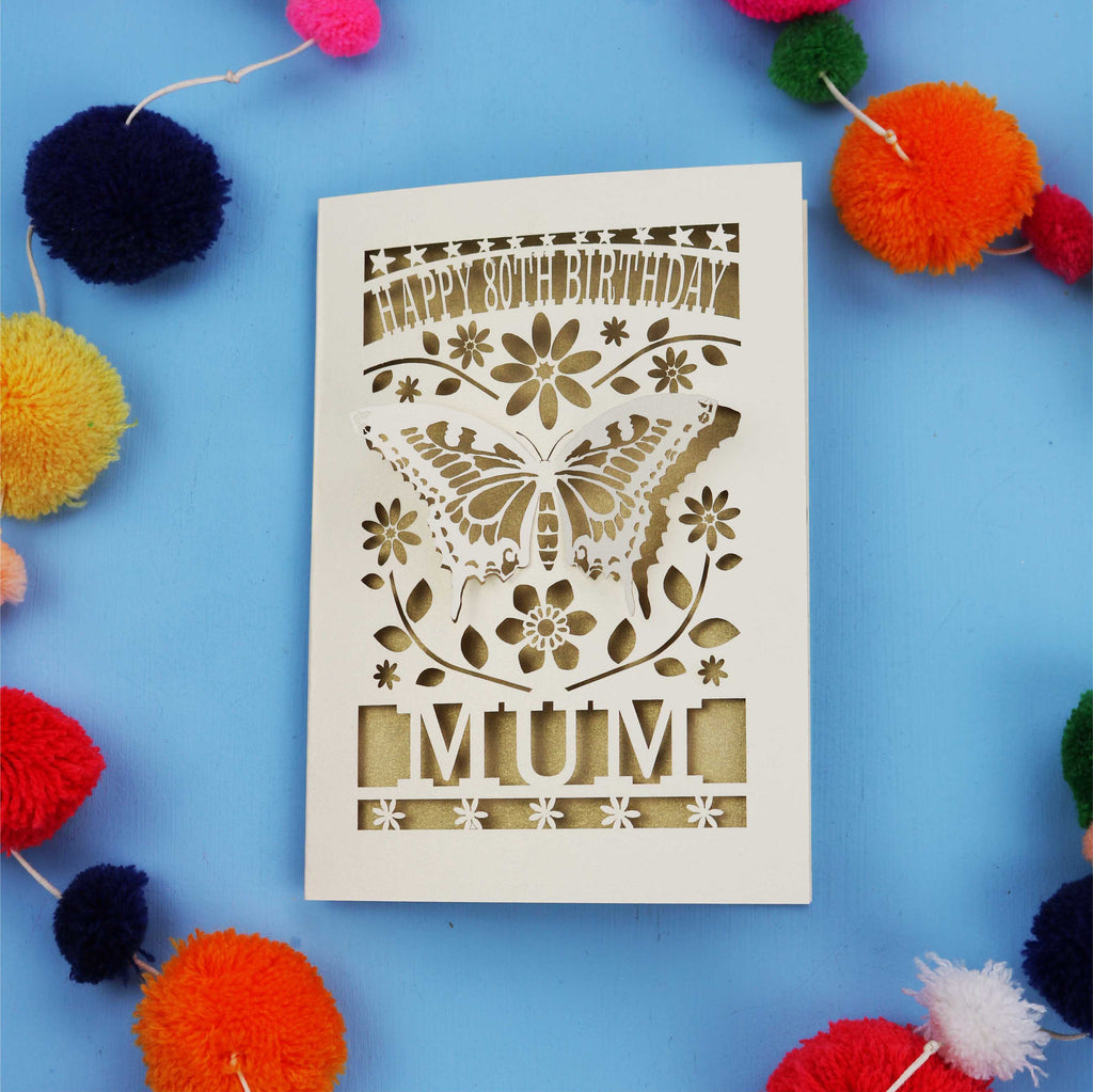 80th Birthday Card with butterfly design and 'Happy Birthday Mum' text on a blue background with colourful pom-poms.