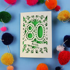 Laser cut 80th Birthday Card with '80' cut out design on a blue background with colourful pom-poms.