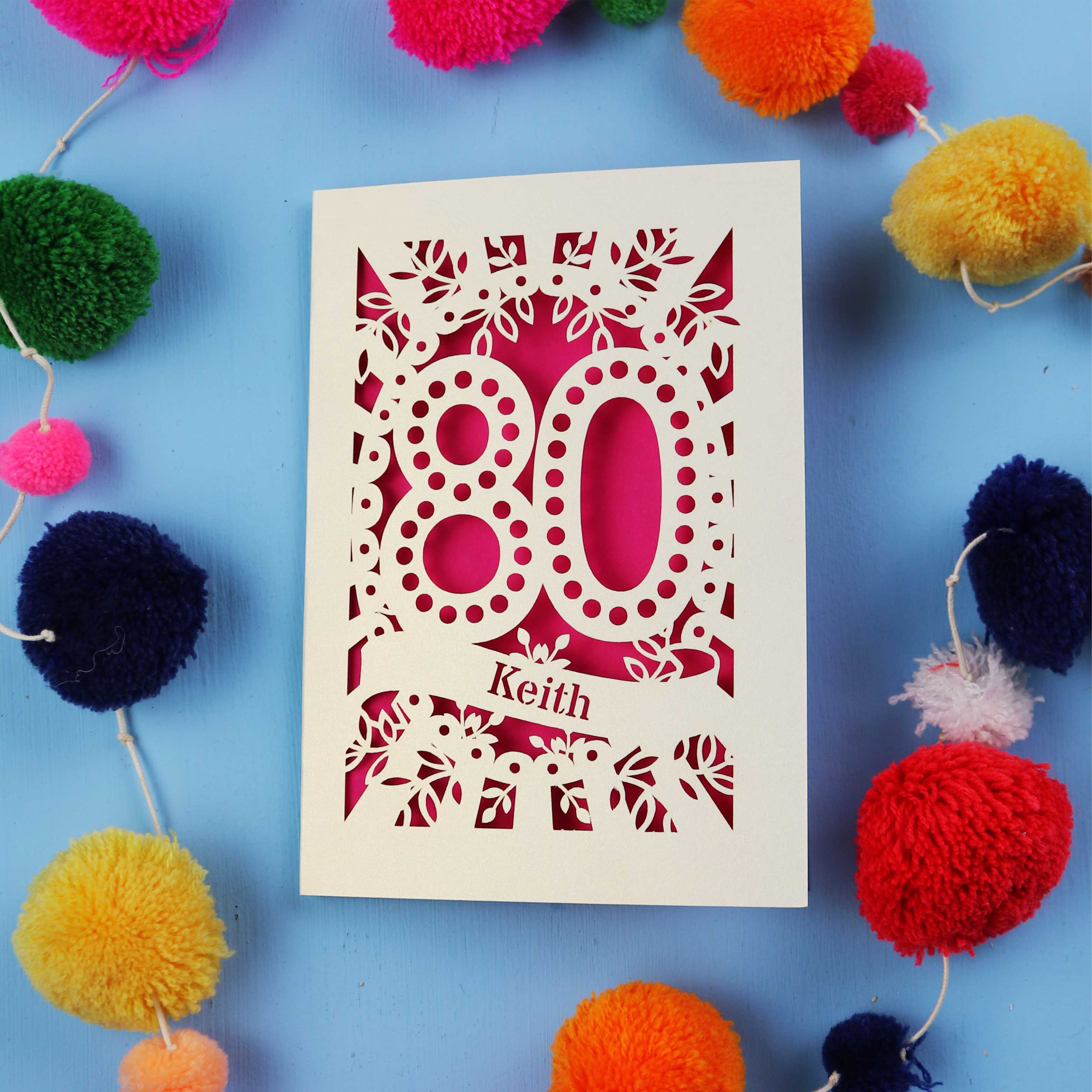 Fun 80th Birthday Card with '80' cut out design on a blue background with colourful pom-poms.