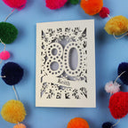Laser cut 80th Birthday Card with '80' cut out design on a blue background with colourful pom-poms.