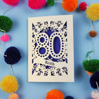 Laser cut 80th Birthday Card with '80' cut out design on a blue background with colourful pom-poms.