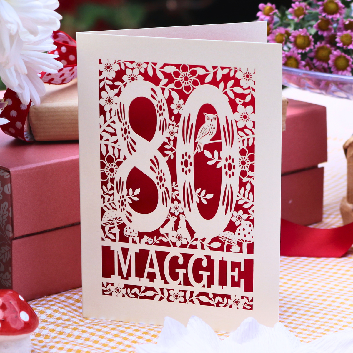 A personalised 80th birthday card. laser cut with the number 80 surrounded by floral elements and woodland creatures, personalised with the name Maggie'
