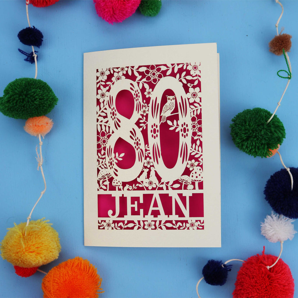 Personalised 80th Birthday card with '80 Jean' design on a blue background with colourful pom-poms.