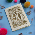 Laser cut Birthday card with 'Happy Birthday 90 Albert' on a blue background with colourful pom-poms and paper clips.