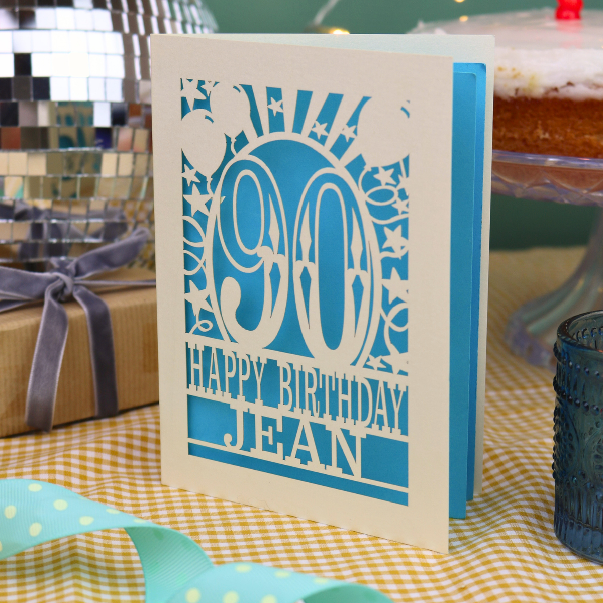 A laser cut 90th birthday card with balloons and stars around a decorative number '90', with personalised text 'Happy Birthday Jean'