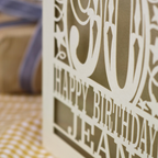 A laser cut 90th birthday card with balloons and stars around a decorative number '90', with personalised text 'Happy Birthday Jean'