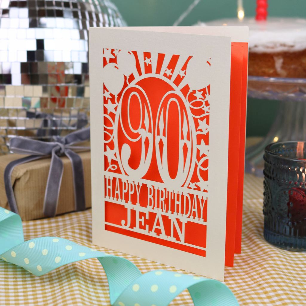 A laser cut 90th birthday card with balloons and stars around a decorative number '90', with personalised text 'Happy Birthday Jean'