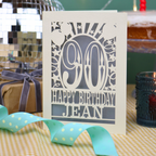 A laser cut 90th birthday card with balloons and stars around a decorative number '90', with personalised text 'Happy Birthday Jean'