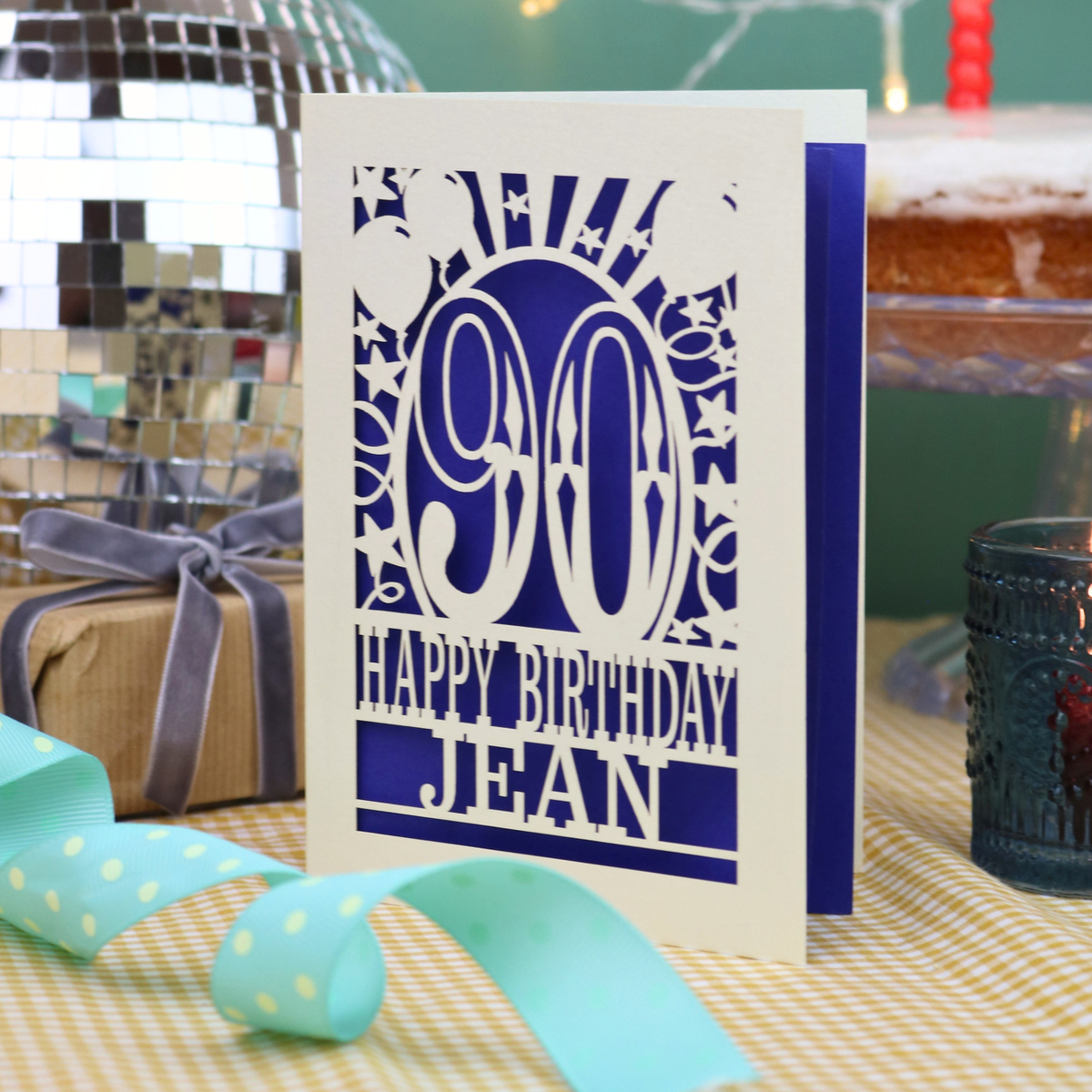 A laser cut 90th birthday card with balloons and stars around a decorative number '90', with personalised text 'Happy Birthday Jean'
