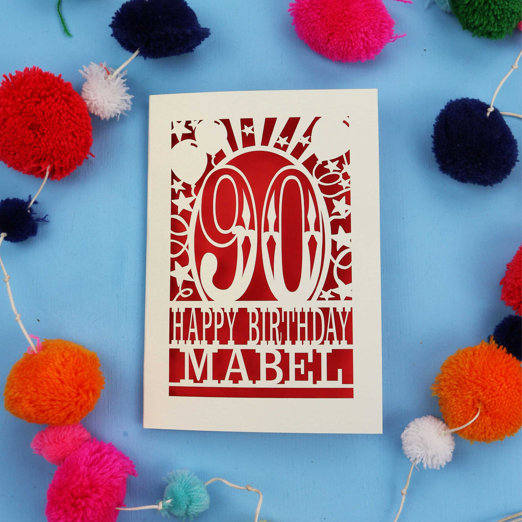 Happy Birthday Mabel - A personalised 90th birthday card with colourful pom-poms on a blue background