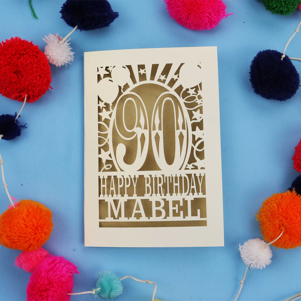 A personalised 90th birthday card with colourful pom-poms on a blue background