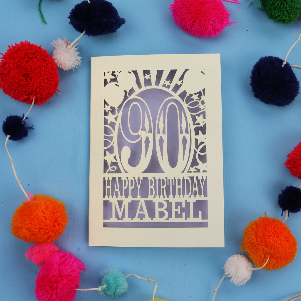 A personalised 90th birthday card with colourful pom-poms on a blue background