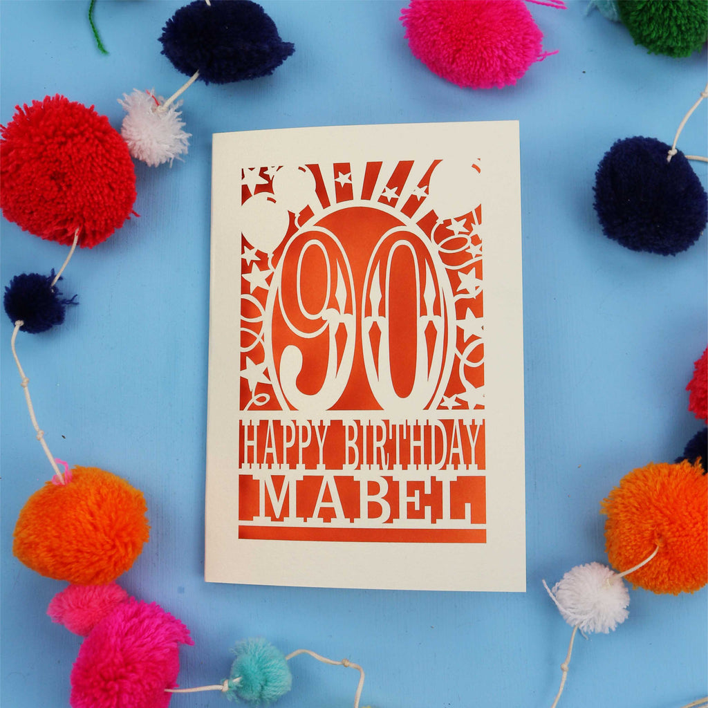 Happy Birthday Mabel - A personalised 90th birthday card with colourful pom-poms on a blue background