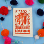 Happy Birthday Mabel - A personalised 90th birthday card with colourful pom-poms on a blue background